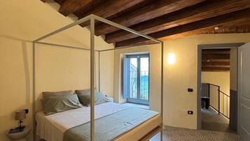 Ein Schlafzimmer mit einem Himmelbett, einem Fenster mit Blick und einem Musterparkett.