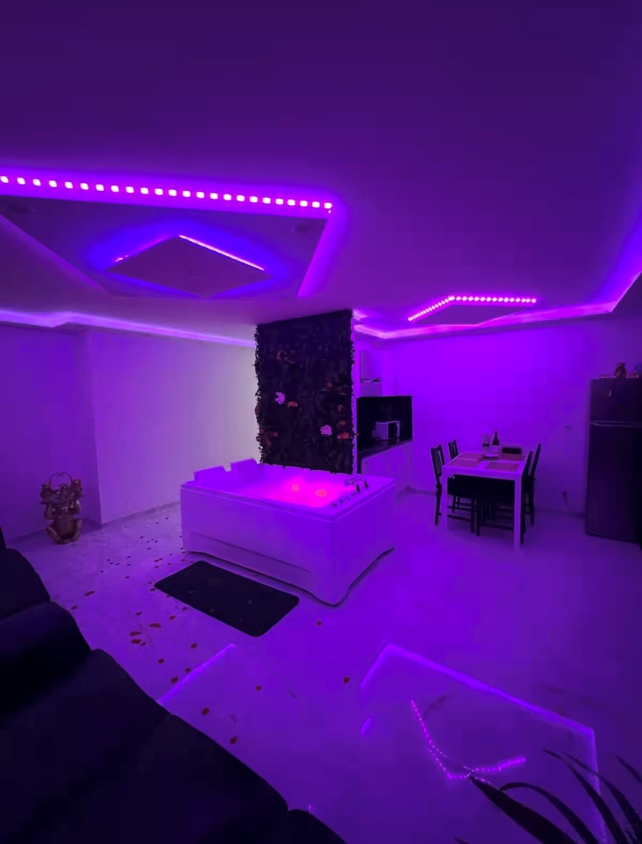 A room with a white sofa, a small table, and a wall-mounted TV.