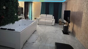 Ein modernes Wohnzimmer mit einer großen weißen Badewanne, einem weißen Sofa und einem Flachbildfernseher.