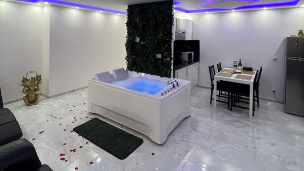 Ein modernes Wohnzimmer mit einer weißen Whirlwanne, einem Essbereich und einer Küche.