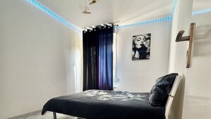 Ein modernes Schlafzimmer mit einem Bett, einem Deckenventilator und LED-Beleuchtung entlang der Decke.