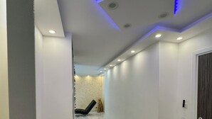 Ein Flur mit weißen Wänden, einem Marmorboden und einer Decke mit Einbuchtungslichtern und blauer LED-Beleuchtung.