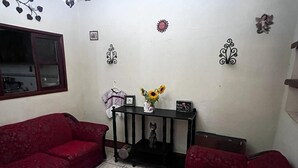 A living room with two red sofas, a small black console table with a vase of sunflowers, and decorative wall art.