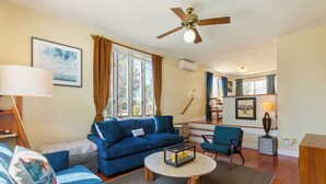 A living room with a blue sofa, a round coffee table, and a ceiling fan.