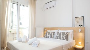 A modern hotel room with a wooden bed, white linens, a pendant light, and a view of the city through large windows. - K11 Apartment in Athens Downtown (Athina)