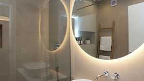 A modern bathroom with a glass-enclosed shower, a white sink, and a large mirror with integrated lighting. - K11 Apartment in Athens Downtown (Athina)