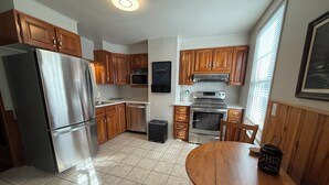 A modern kitchen with wooden cabinets, stainless steel appliances, and a tiled floor. - Past Meets Posh at The Phoenix Loft (Halifax)