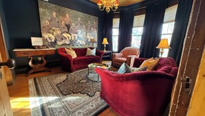 A living room with a red sofa, a red armchair, a patterned rug, a chandelier, and a painting on the wall. - Past Meets Posh at The Phoenix Loft (Halifax)