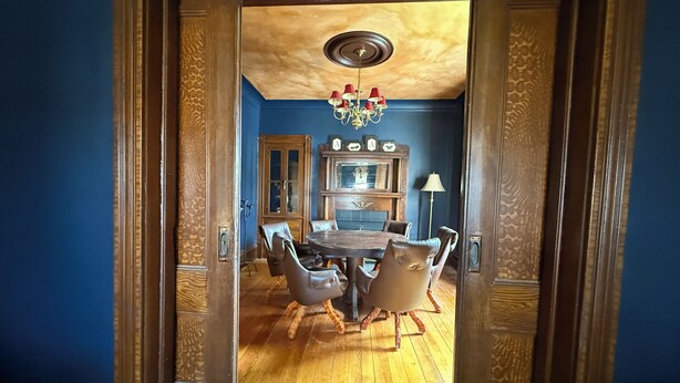 A dining area with a wooden table and chairs, a chandelier, and a blue wall. - Past Meets Posh at The Phoenix Loft (Halifax)