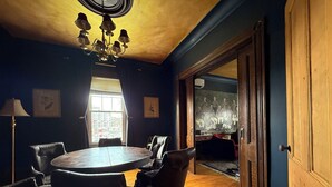 A room with a round table, leather chairs, a chandelier, a large window, and a door leading to another room. - Past Meets Posh at The Phoenix Loft (Halifax)