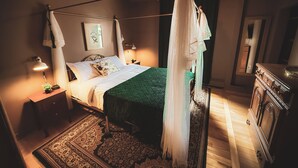 A four-poster bed with a canopy, bedside lamps, a nightstand with a plant, and a wooden dresser. - Past Meets Posh at The Phoenix Loft (Halifax)