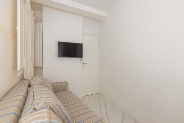 Een kamer met een bed, een aan de muur bevestigde televisie en een deur.