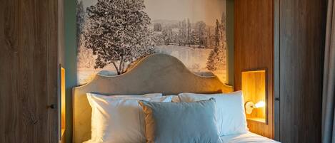 Een net opgemaakt bed met witte lakens en kussens, een hoofdbord met een houtsnijdecoratie, en een wandlamp.