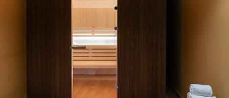 Una habitación con un armario de madera, una cama con ropa de cama blanca y un par de toallas sobre un banco.
