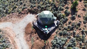 A geodesic dome structure with a central pole, surrounded by a deck with seating.