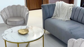 Una sala moderna con un sofá gris, una mesa de centro de mármol redonda y un sillón a juego.