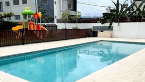 Una piscina rectangular con agua azul cristalina, rodeada por una solana con baldosas.