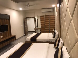 A hotel room with two beds, a flat-screen TV, a wooden panel wall, and a mirror.