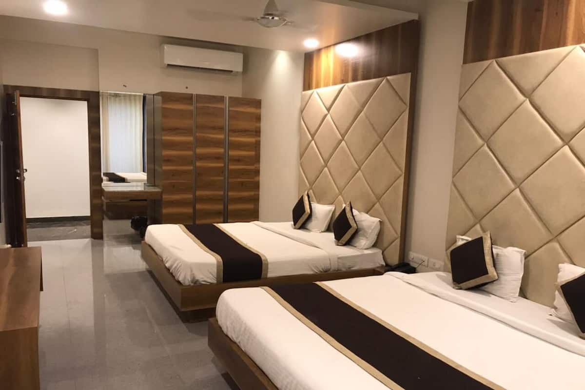 A hotel room with three beds, a wooden wardrobe, a mirror, and a ceiling fan.