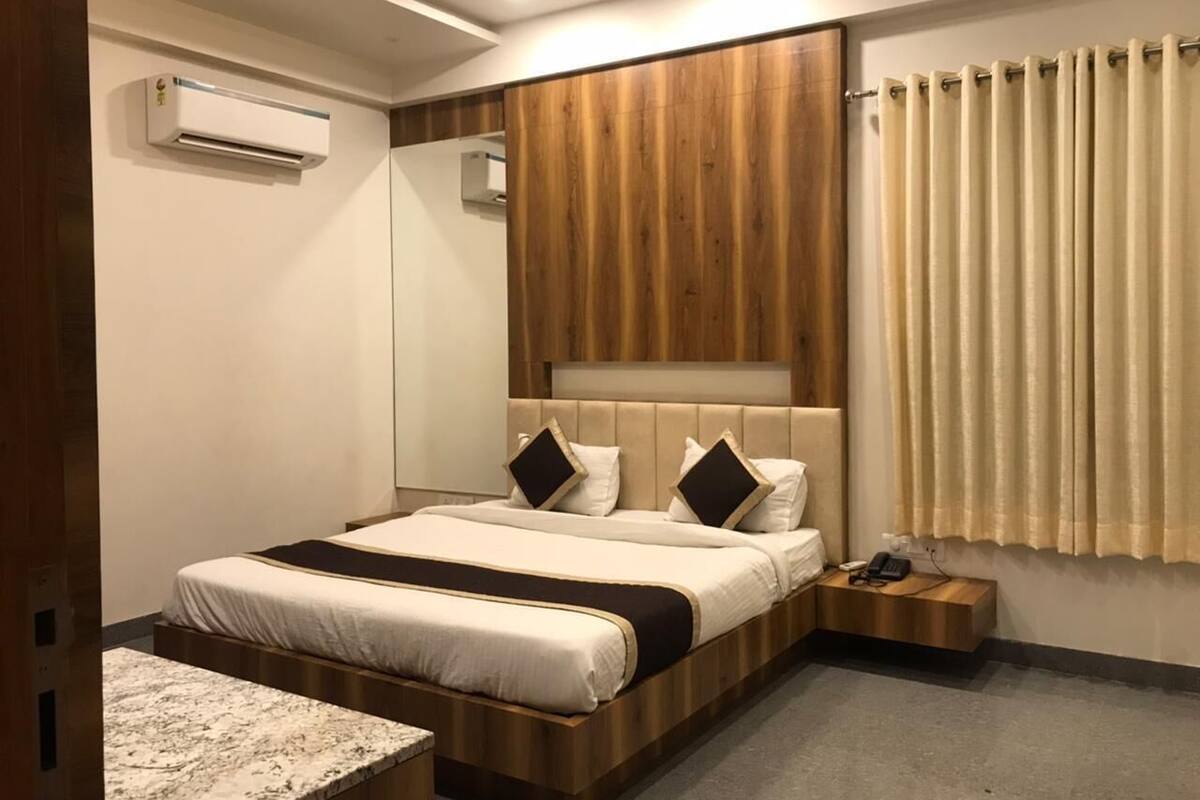 A modern bedroom with a large bed, bedside tables, a wooden headboard, and a window with curtains.