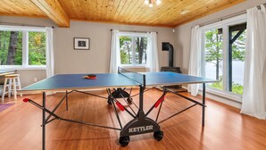 A ping pong table in a room with wooden flooring and a wooden ceiling.
