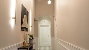 A hallway with a checkered floor, a black console table with decorative items, and pendant lighting. - Monteroduni 22 - Chiaia Design Rooms (Naples)
