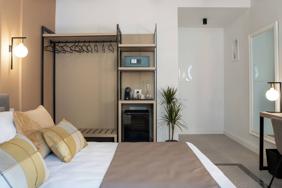 Una habitación de hotel moderna con cama, escritorio, cafetera y una planta.