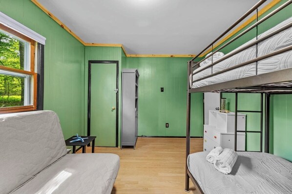 Un dormitorio con literas, un sofá, una mesita y una puerta que da a un pasillo.