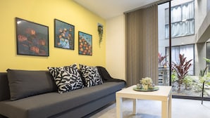 A modern living room with a grey sofa, a white coffee table, and three framed artworks on the yellow wall.