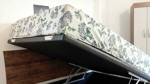 A bed with a built-in storage drawer, an air conditioning unit on the wall, and a wooden panel on the headboard. - APARTMENT ACONCHEGO, NEXT TO NORTH SHOPPING AND DOWNTOWN MARACANAU (Jereissati II Maracanaú)