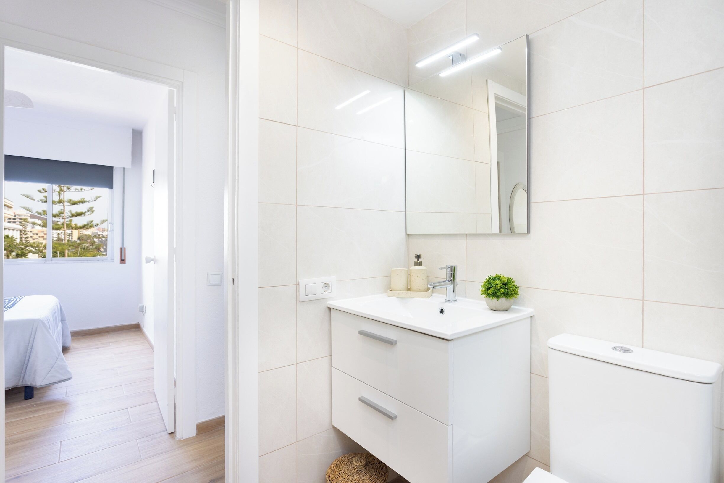 Une salle de bain moderne avec un meuble-lavabo blanc, un miroir et des toilettes.