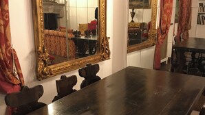 A dining area with a long wooden table and ornate gold-framed mirrors on the walls.