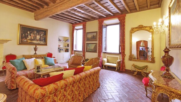 A traditional room with a sofa set, a wooden ceiling, a large mirror, and a bookshelf.