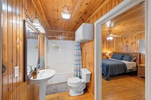 Un baño de cabaña de madera con ducha, inodoro y lavamanos.