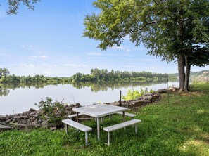 Una mesa de picnic junto a un lago tranquilo con un árbol cercano.