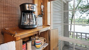 Una cocina de madera con una cafetera, un hervidor y una taza sobre la encimera.