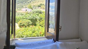 A room with a bed, a window with a view of a mountainous landscape, and a curtain. - Lighthouse Villa (Santa Flavia)