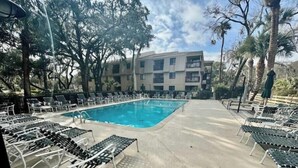 A swimming pool with lounge chairs and a building in the background.