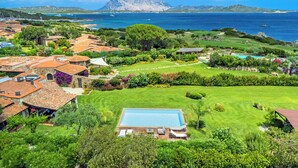 A coastal property with a swimming pool, lush gardens, and a view of the sea and mountains. - Exclusive villa with pool and sea view in Puntaldia ( San Teodoro) (Puntaldia)