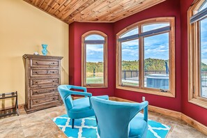 A room with a red wall, two large windows, a wooden ceiling, a blue chair, and a wooden cabinet. - Lakefront - Pool & Dock. 10+Private acres. (Dandridge)