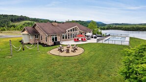 A lodge with a stone exterior, outdoor seating, and a view of a lake.