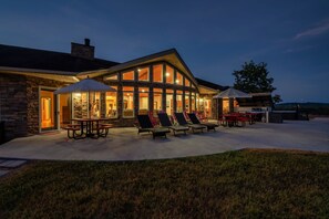 A stone house with a covered patio area, outdoor seating, and a grill. - Lakefront - Pool & Dock. 10+Private acres. (Dandridge)