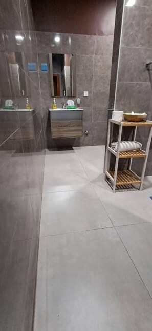 A modern bathroom with a marble vanity, a wooden shelf, and a mirror. - The Big Blue Resort & Spa (Nyanyanu)