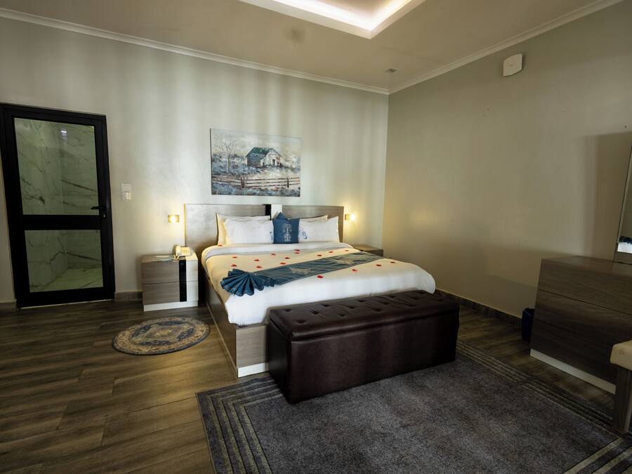 Una camera da letto moderna con un letto, comodini, una panca, una cassettiera e un quadro appeso al muro.