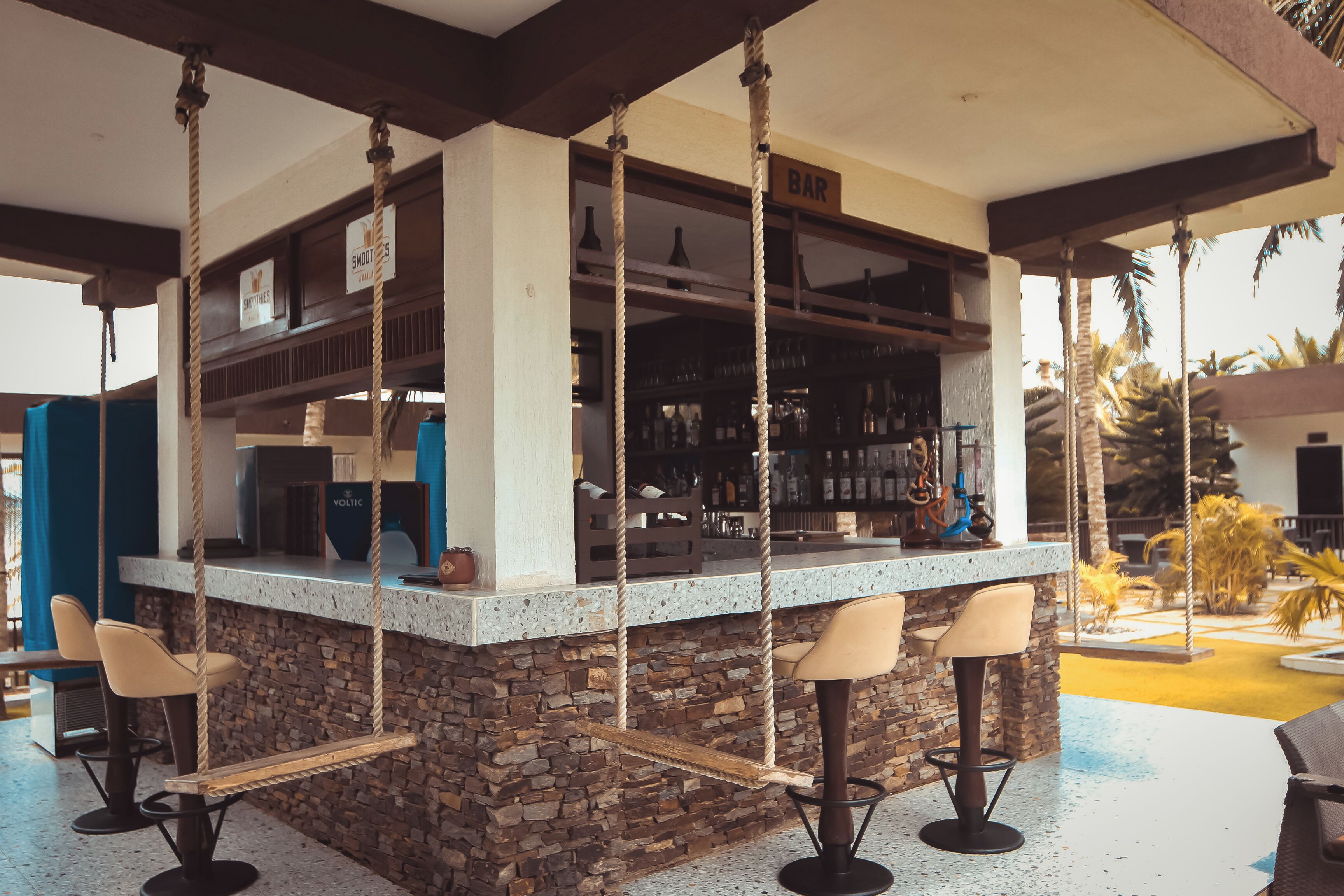 A bar area with a stone counter, bar stools, and a swing seating area.