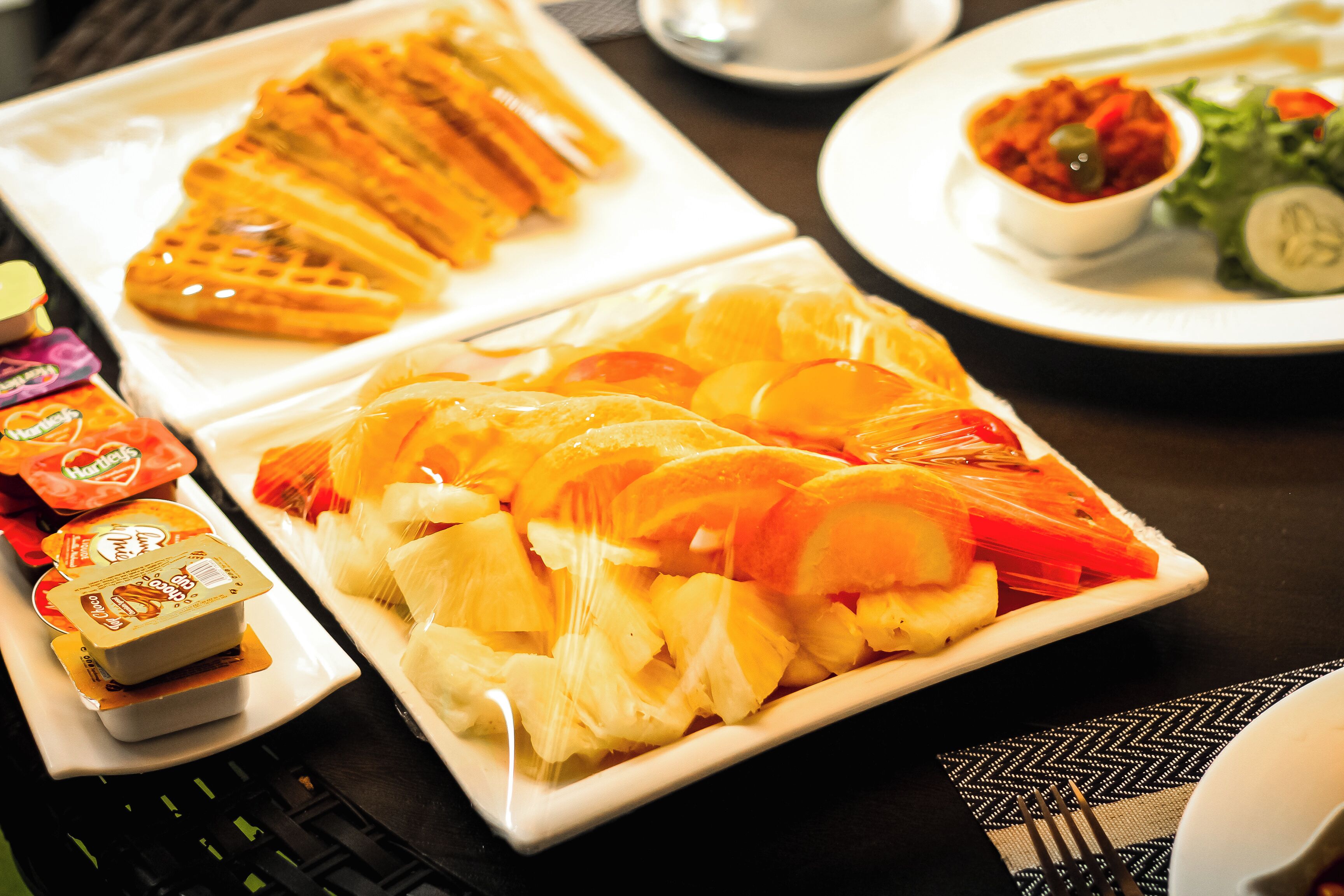 Un buffet de petit-déjeuner avec des gaufres, des fruits et des viennoiseries.