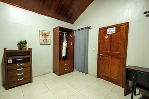 Una habitación con un armario de madera, un perchero, una puerta con un letrero y una mesita.