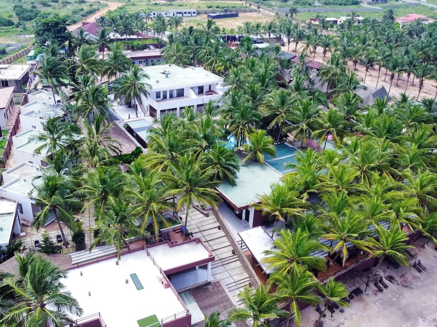Zona residencial con varias casas, una piscina y palmeras.