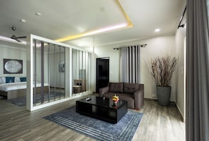 A modern living room with a sofa, a coffee table, a TV, and a sliding glass door leading to a bedroom. - The Big Blue Resort & Spa (Nyanyanu)