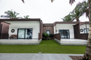 A modern building with two separate units, each featuring a sliding glass door, a small patio area, and a seating bench. - The Big Blue Resort & Spa (Nyanyanu)